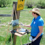 Workshop participant is oil painting Mt. Shasta at The Grand View Workshop outside in a field.