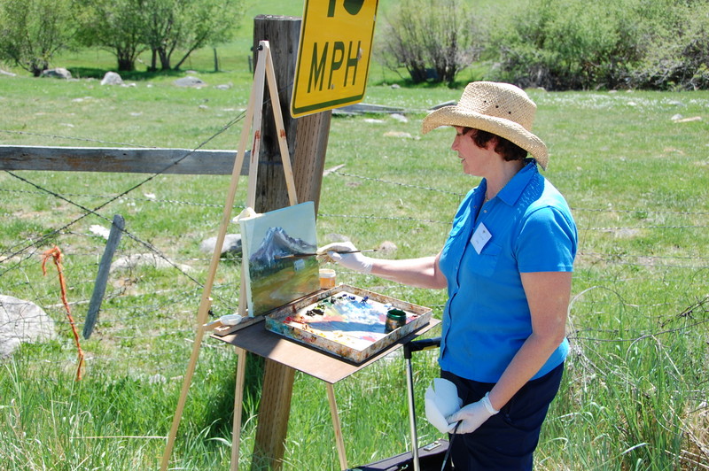 Workshop participant is oil painting Mt. Shasta at The Grand View Workshop outside in a field.