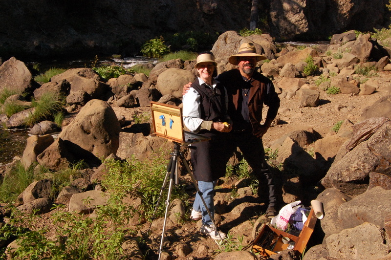 This is a photo of a participant oil painting on location at The Grand View Workshop with Stefan Baumann beside her.