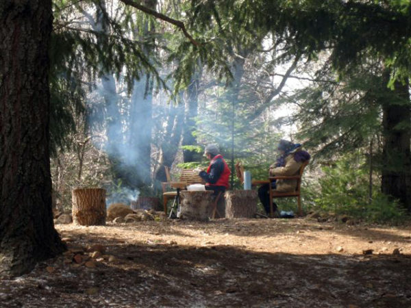 This photo shows artists who are warming up by a camp fire during a Spring Workshop at the Grand View Ranch.